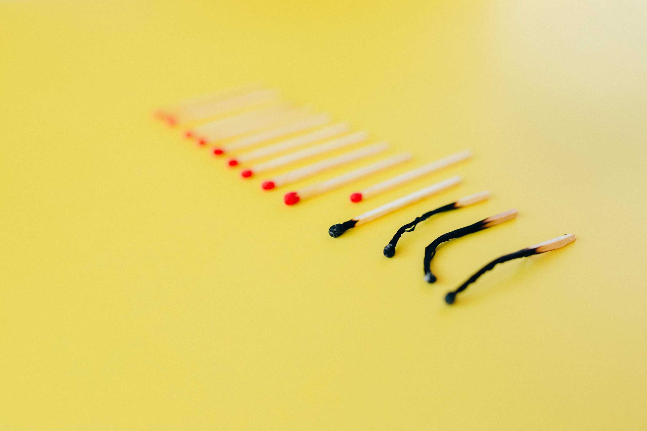 pexels-n-voitkevich-6837571 A row of matches on a yellow background, with unlit red-tipped matches followed by several burnt matchsticks, symbolizes enriching workplaces by empowering people to prevent burnout and foster a supportive environment.