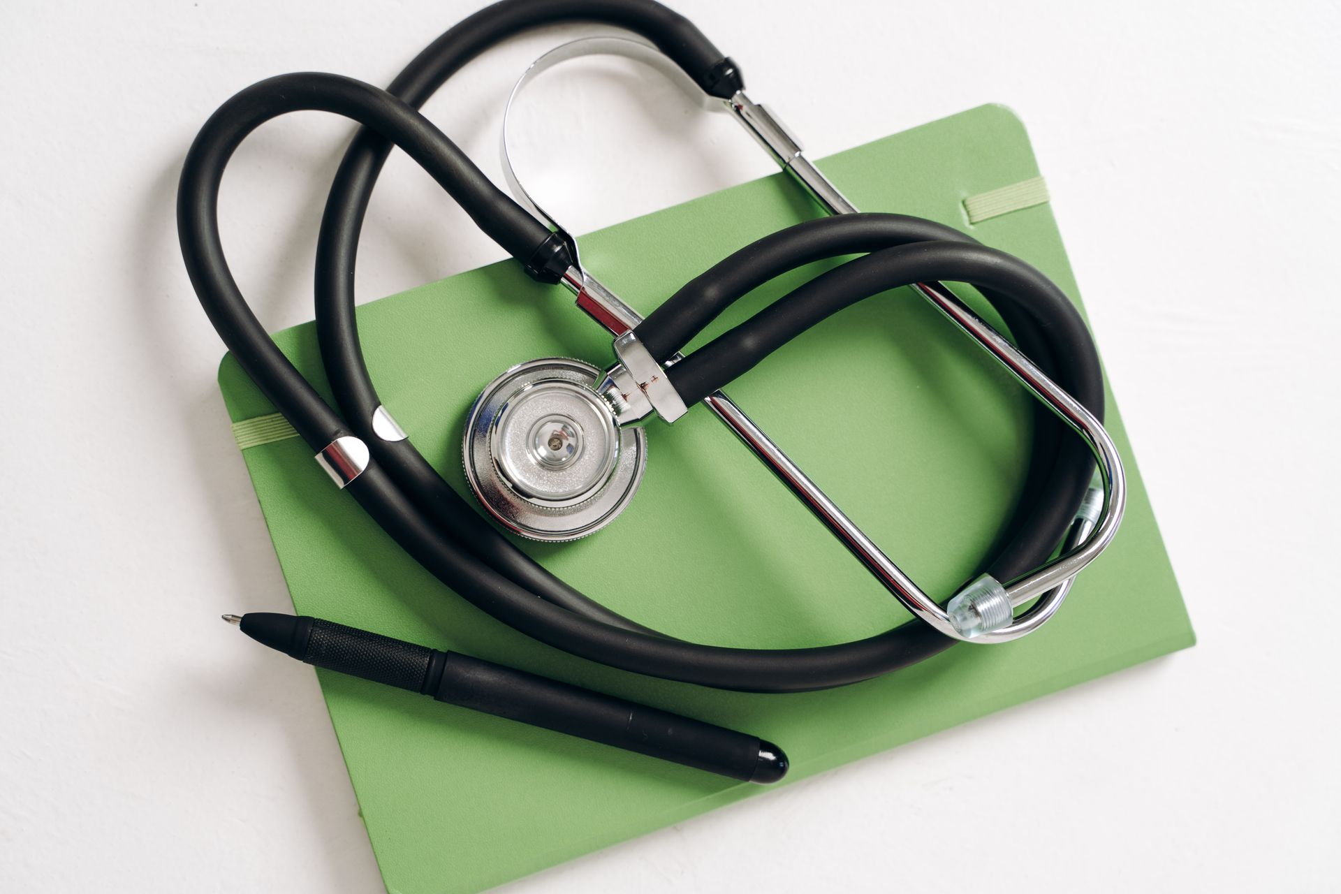pexels-tessy-agbonome-521343232-19963293 Top view of a stethoscope and pen on a green notepad, ideal for medical and educational themes